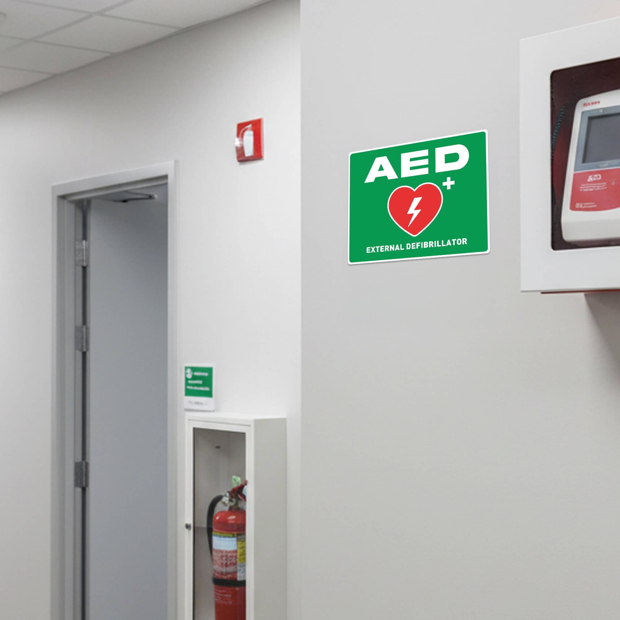 Green AED sign next to an AED in an office