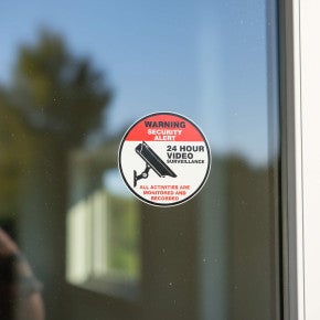 A vinyl sticker for 24-hour security surveillance on a storefront window