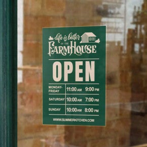 A green window cling on a window for a restaurant with the store hours