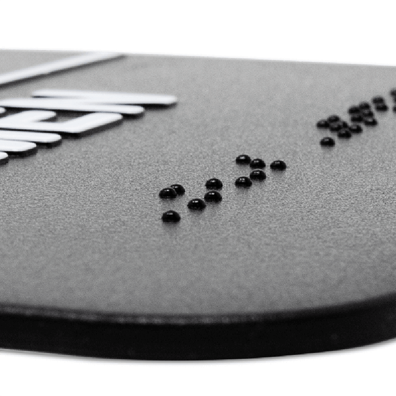 Close up on the braille on the ADA restroom sign