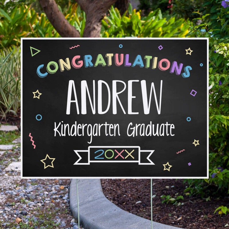 Colorful kindergarten graduation yard sign displayed next to pavement