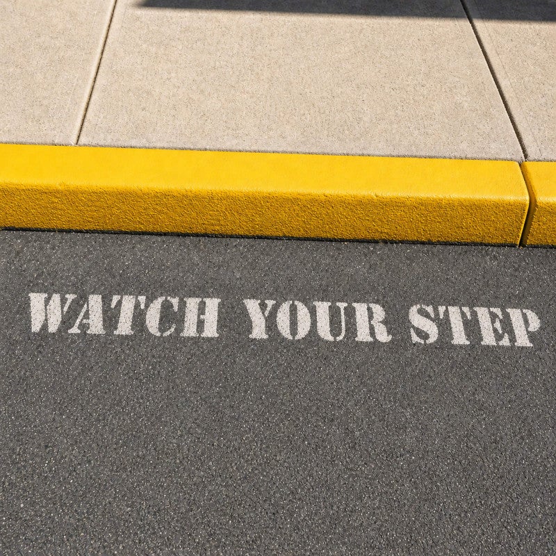 Watch Your Step stenciled onto a sidewalk