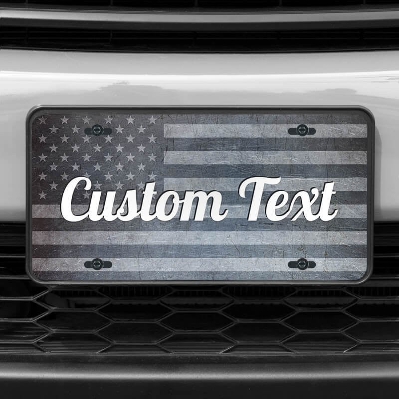 A close up of the Custom American Flag front license plate on a white car