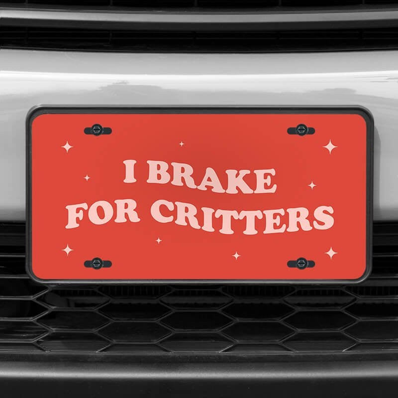 A close up of the I Brake For Critters front license plate on a white car