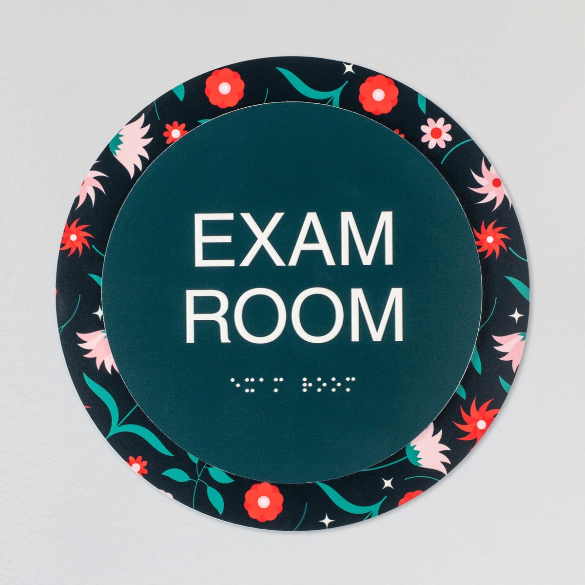The custom round 2-layered ADA sign hanging on a wall for an exam room