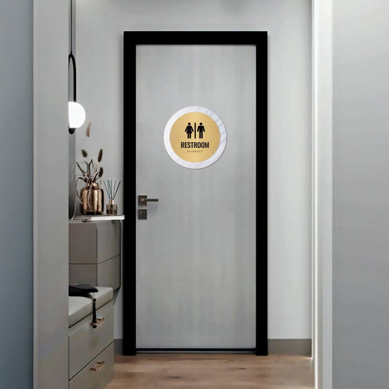 A large 2-layer round ADA sign for a restroom on the outside of a door