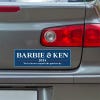 Barbie and Ken bumper sticker below a gray car's tail light