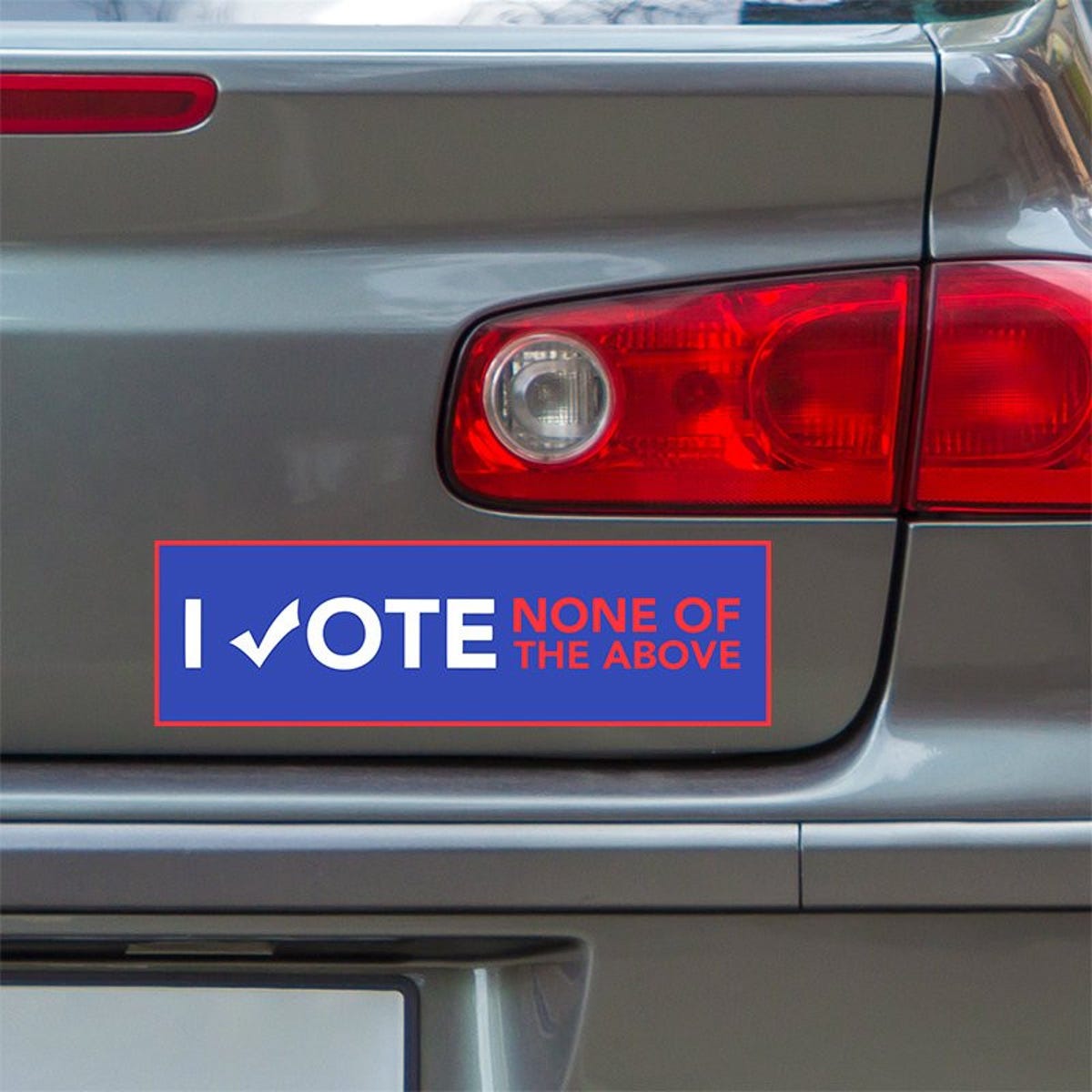 None of the Above Political Bumper Sticker below a gray car's tail light