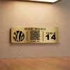 A small gold engraved plastic sign with a QR code for a restaurant menu