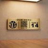 A small gold engraved plastic sign with a QR code for a restaurant menu