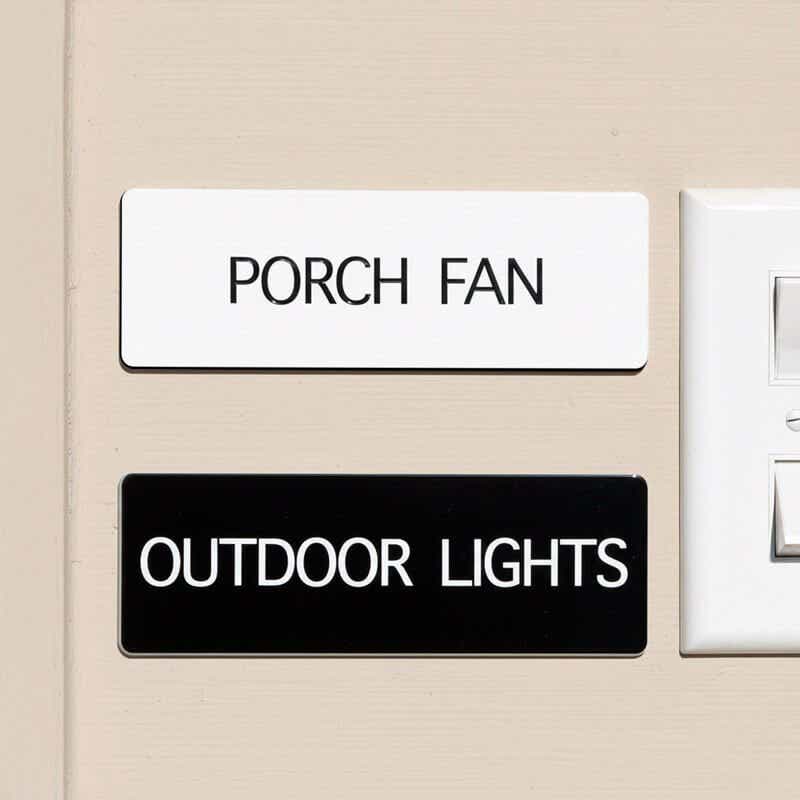 White and black engraved plastic signs being used to label and porch fan and outdoor lights
