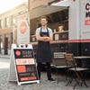 A sandwich board sign for a food truck placed 
