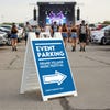 An event parking sandwich board for a music festival displayed in a parking lot