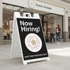 A now hiring sandwich board sign in front of a beauty boutique