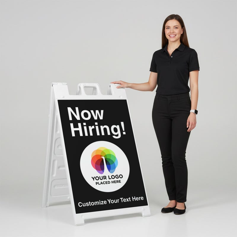 A woman standing next to an A-frame sign with her hand on the top of the sign