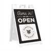 A sandwich board sign for a farmhouse that says We Are Open and features their logo
