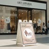 A sidewalk sign for an apparel store displayed outside