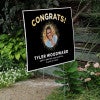 Sunburst graduation yard sign displayed next to stairs