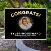 Sunburst graduation yard sign displayed next to pavement