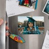 Hand placing a Custom Photo Graduation Announcement photo magnet on a stainless steel refrigerator
