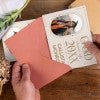 Personalized Modern Minimalist Graduation Announcement photo magnet being placed into a rose colored envelope