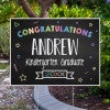 Colorful kindergarten graduation yard sign displayed next to pavement