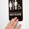 A person's hand feeling the Braille on the sign