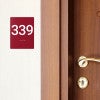 A red ADA sign with a room number