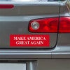 Make American Great Again Bumper Sticker below a gray car's tail light