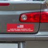 American Flag Funny Political Bumper Sticker below a gray car's tail light
