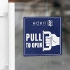 A blue window cling to pull to open on a glass door