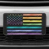 A close up of the LGBTQ Pride American Flag front license plate on a white car