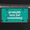 A close up of the Probably Late front license plate on a black car