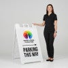 A woman standing next to an A-frame sign with her hand on the top of the sign