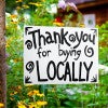 A custom made yard sign for a local vendor by a garden