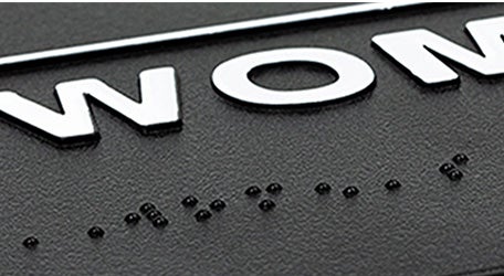 Close up of the braille and tactile characters on a women’s restroom sign